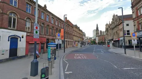A road through a city centre with buildings on each side. 