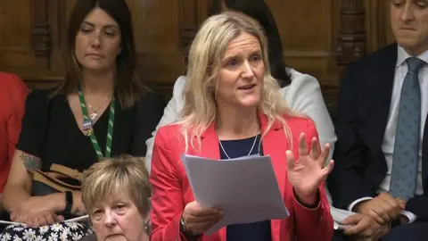 PA Kim Leadbeater MP stands in the Commons, holding papers while talking about the bill, wearing a pinkish-red blazer on Friday 20 June, 2025