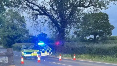 A rural stretch of Ashby Road near Barwell with a police road block in place