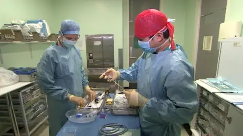 BBC A surgeon from the US airbase (on the left) works with a British colleague