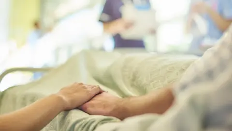 Getty Images Patients holding hands at hospital bedside