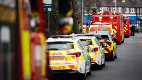 Getty Images A view of police and fire emergency service vehicles, with various yellow and red markings, parked along a road near the substation