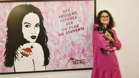 WireImage via Getty Images Miss. Tic poses with her dog in front one of her works in Paris, France. Photo: May 2018