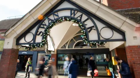 Exterior entrance of Swan Walk shopping centre with shoppers in the foreground.