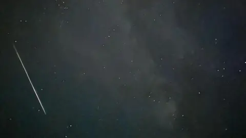 CAMILLA BRAHDE A night sky, a shooting star moves on the left side of the image