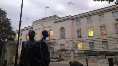 General view of the exterior of Hackney Town Hall on Mare Street. A statue of two people is visible in front of the building