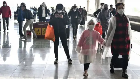 AFP Passengers arrive at the railway station in Wuhan, China's central Hubei province on 28 March 2020, after travel restrictions into the city were eased