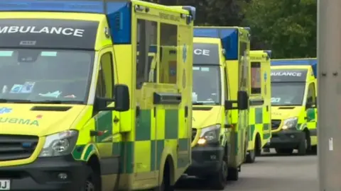 Several ambulances in a line outside a hospital