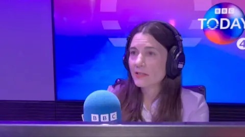 Lauren Schultz in a white top wearing black headphones in a radio booth