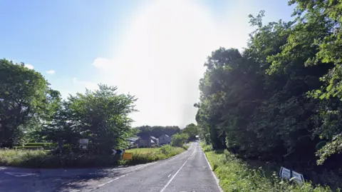 Google The A5012, a long and straight tree-lined country road with a turn off to the left-hand side
