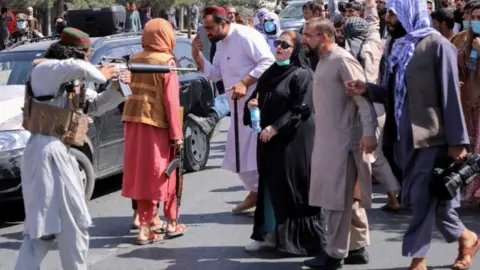 Reuters A Taliban fighter points a gun at a woman during a demonstration in Kabul