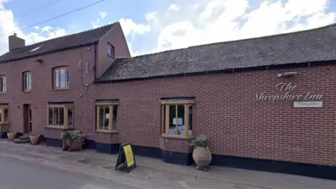 The side of a red bricked pub, with the words The Shropshire Inn in gold lettering on the side