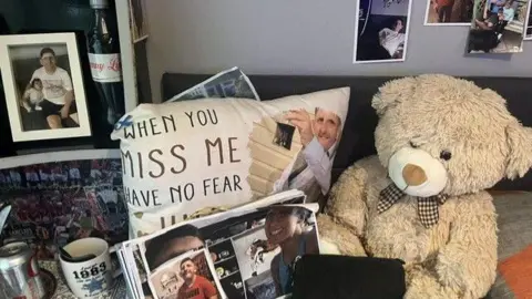 Dom Cotter A teddy bear, pillow and various photographs paying tribute to a young man who can be seen smiling in the photos.
