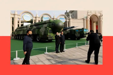 Reuters Visitors pose for pictures near displays of military vehicles carrying DF-41 intercontinental ballistic missile and DF-17 hypersonic missile at an exhibition