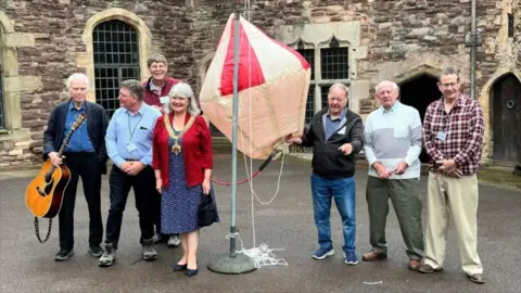 Group of people surrounding a old-fashioned style balloon.