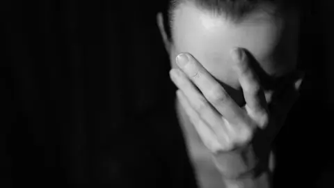 Getty Images Woman holding head in her hand - posed - black and white image