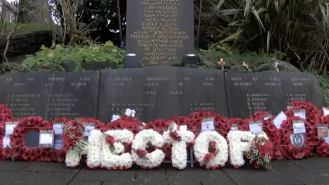 BBC Floral tribute spelling Hector in from of Onchan war memorial