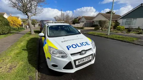 Shaun Whitmore/BBC A police car near the scene at Grayson Avenue, Pakefield, Suffolk