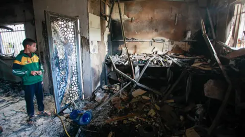 Getty Images Palestinian inspects the damage inside a destroyed house in the Jenin refugee camp after it was targeted by the Israeli army on 13 December