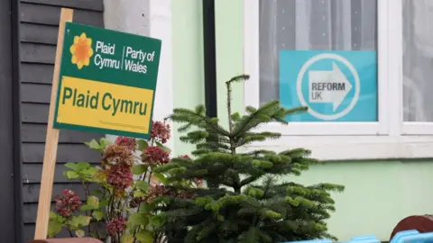 Plaid Cymru and Reform UK signs in the windows of houses in Caerphilly, Wales