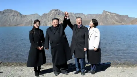 Reuters Moon Jae-in and Kim Jong-un hold hands at the top of Mt Paektu in North Korea (Oct 2019)