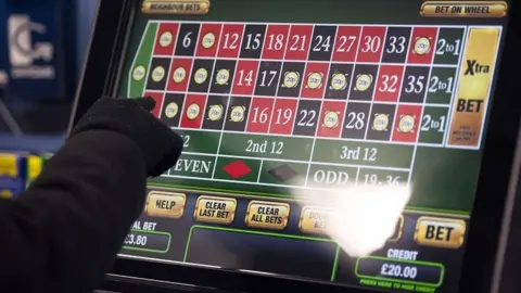 PA A hand presses the screen of a fixed odds betting terminal