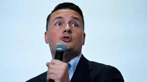 Britain’s former Health Secretary Wes Streeting delivers a keynote address on 16 May, with a microphone held in his hand.