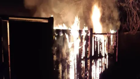 Fire ripping through wooden fencing at night