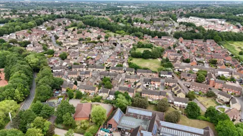Shaun Whitmore/BBC A drone image gives a bird's eye view of an area of housing lined by large, green trees, with some park areas between the housing.
