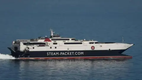 A close-up of the Manannan sailing. It is a sleek catamaran which is white, black and red, and has the Steam Packet written on the side.