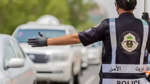 AFP File photo shows a Saudi police officer directing traffic in Mecca (26 July 2020)