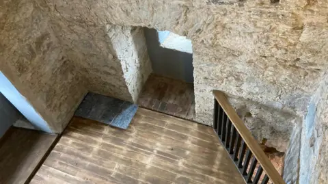 Stone walls and wooden flooring is seen in a section of the fort.
A wooden banister is also seen in the corner.