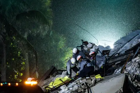 Getty Images Search and Rescue personnel pull a body out of the rubble after the partial collapse of the Champlain Towers South in Surfside, north of Miami Beach, on June 24, 2021.