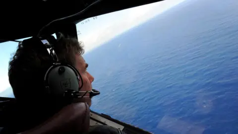 Getty Images Co-pilot and Squadron Leader Brett McKenzie of the Royal New Zealand Airforce (RNZAF) P-3K2-Orion aircraft, helps to look for objects during the search for missing Malaysia Airlines flight MH370