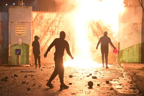 Charles McQuillan / Getty Images Youths set fire to a peace wall in Belfast