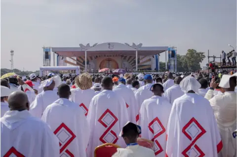 AFP A group of priests wearing their clerical attire facing the stage. They are surrounded by crowds.