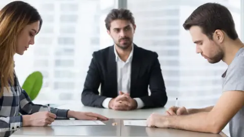 Getty Images Couple signing decree papers getting divorced in lawyers office - stock photo