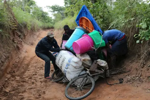 Reuters Congolese migrants expelled from Angola attempt to push a rented bicycle to transport their belongings along the dirt road to Tshikapa, Kasai province near the border with Angola in the Democratic Republic of the Congo, October 12, 2018.