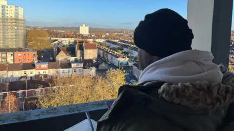 BBC Resident looking out of a window with their back to the camera