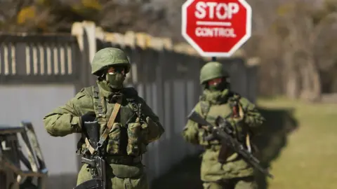 Getty Images Armed soldiers without identifying insignia keep guard outside a Ukrainian military base in the town of Perevevalne near the Crimean city of Simferopol on March 17, 2014