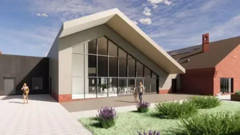 Exeter City Council An artists impression of the hub. It has a slanted roof and a big glass window where there are lots of tables and chairs inside. There is an outside area with a patio area and a grass section with flowers in it. 