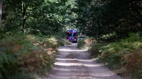 Nottinghamshire Fire and Rescue Service A path in the middle of woodland with a fire engine in the distance.