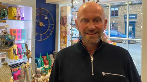 Craig Smith in his gift store on Mill Street with Christmas products in the background.
