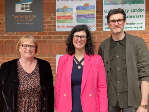 Sonya Zyssemich and Chris Fulton stand either side of Layla Moran MP outside a school