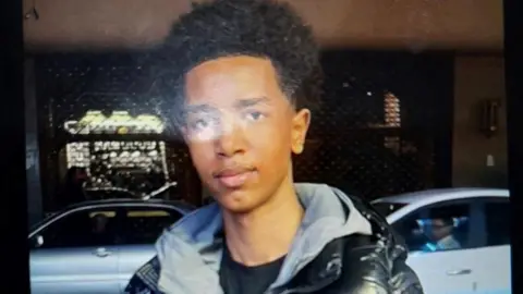A photograph of a boy missing in Sheffield. He is black and has an Afro hair style and is wearing a grey hooded top and black puffa-style jacket