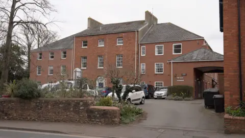 An exterior shot of the Old Vicarage in Wellington - it is a three storey building with large Victorian style windows