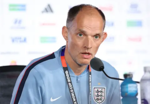 Thomas Tuchel looking serious sat at a press conference with visible stand up microphone