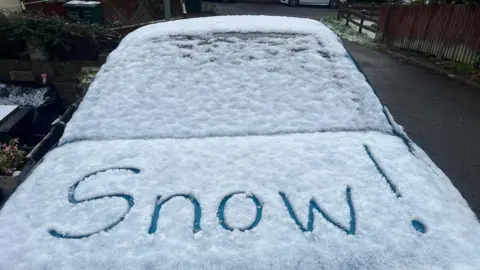 BBCWeatherWatchers/LittleLeo The words snow are etched out into a snow covered back of a car