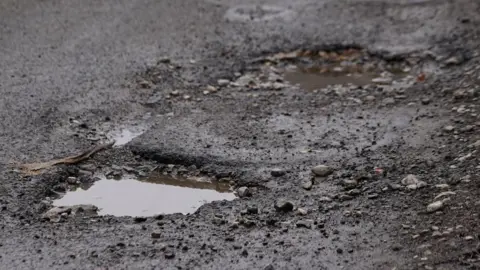 Oli Constable/BBC Potholes filled with water in a road