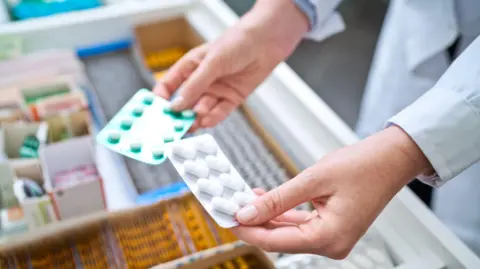Pharmacists holding pills in hands above drawer with medicines. Close up of hands, unrecognisable person.
